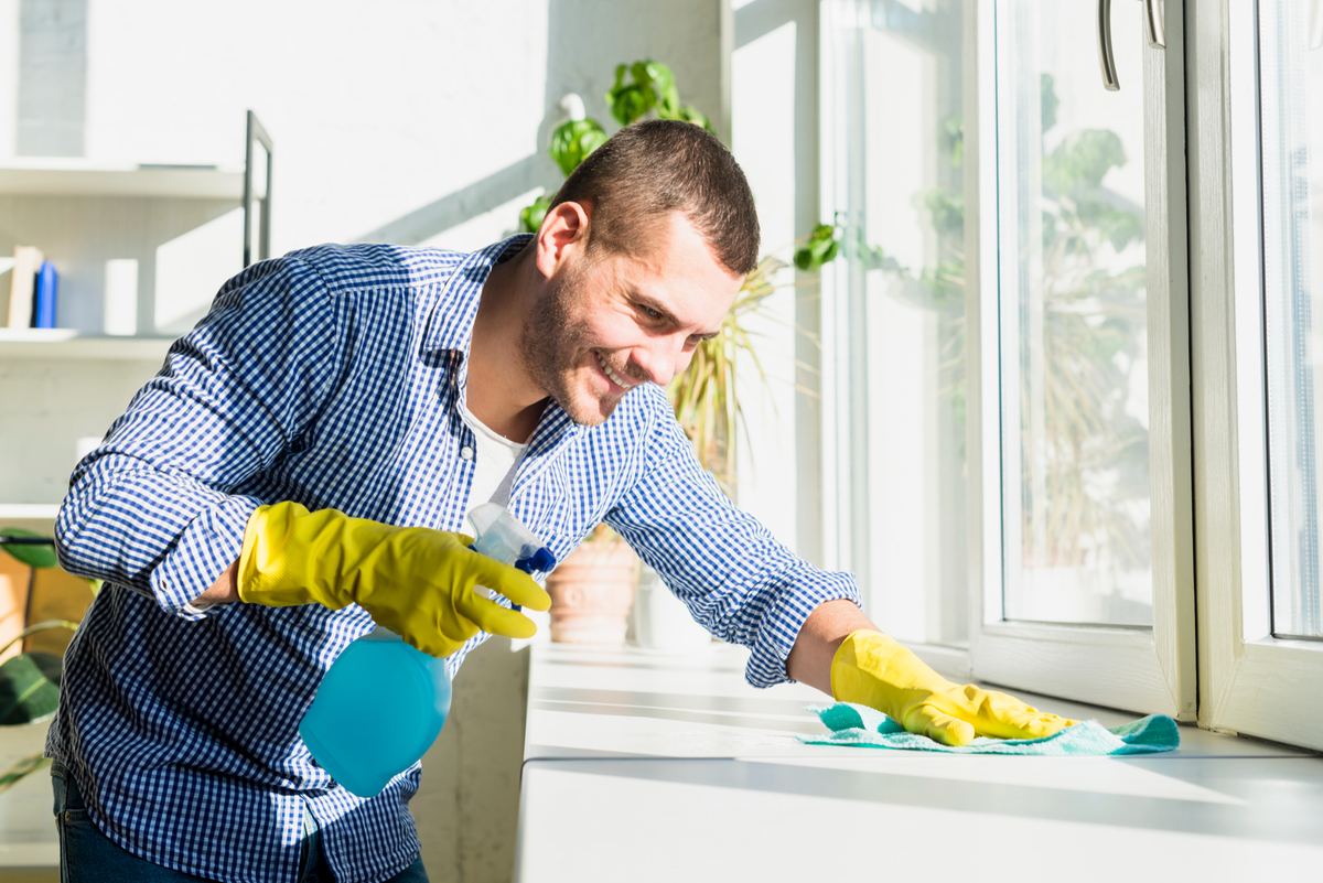 Un intervenant nettoie un rebord de fenêtre avec des gants